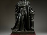 une statue en bronze représentant un homme assis sur une chaise