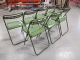 several green folding chairs in a warehouse with orange couches in the background