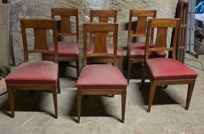 six chaises en bois avec des assises rembourrées rouges dans une pièce