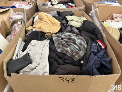 de nombreux cartons remplis de vêtements qui traînent par terre