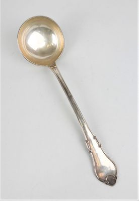 cuillère en argent avec un manche, posée sur une surface blanche