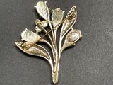 a close up of a brooch with flowers and leaves on it