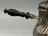 a silver tea pot with a wooden handle on a table