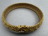 a close up of a gold bracelet on a gray surface