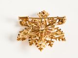 gold plated snowflake brooch on white background