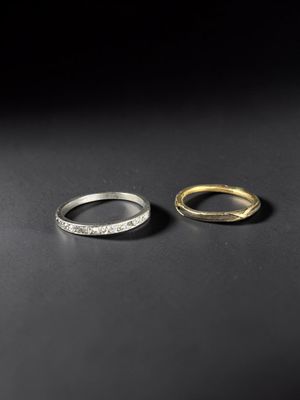 two gold and silver rings on a black surface