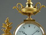 a gold clock sitting on top of a table next to a vase
