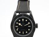 une photo d'une montre noire montée sur un bracelet en cuir noir