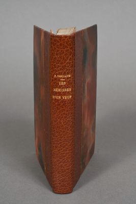 an old brown book sitting on top of a table next to a gray wall