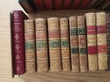 several old books are lined up in a row on a shelf