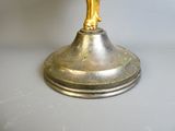 une figurine en or posée sur un plateau en argent, sur une table