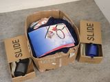 une boîte en carton remplie de vêtements et d'autres objets, posée par terre