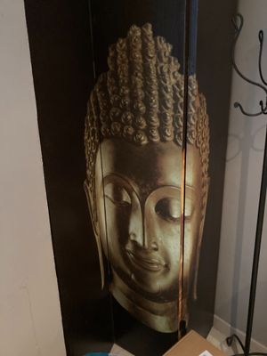 une photo d'une statue de Bouddha accrochée au mur à côté d'une table