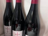 trois bouteilles de vin rouge sont alignées sur une étagère