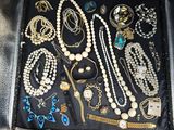 an open suitcase filled with lots of jewelry sitting on top of a wooden floor