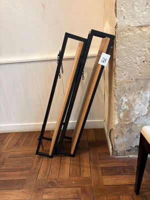 two wooden frames leaning against a wall next to a chair