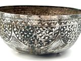 a silver bowl that is sitting on a white surface