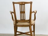 a wooden chair with a beige seat on a carpeted floor