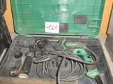 une boîte à outils verte posée par terre, contenant des outils