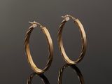 a pair of gold hoop earrings on a reflective surface
