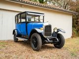 une vieille voiture bleue garée devant un garage