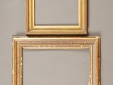 two gold picture frames on a gray wall