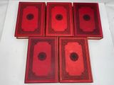 six red books are lined up in a row on a white surface