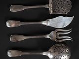 quatre fourchettes et cuillères sont alignées sur une surface noire