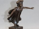 bronze statue of a woman in a dress and hat on a black base