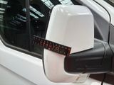 a measuring tape on the side mirror of a white car