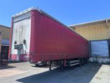 une semi-remorque rouge garée devant un immeuble