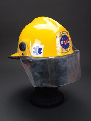 casquette jaune sur laquelle est fixé un casque, posée sur une surface noire
