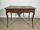 une vieille table en bois avec un tiroir en dessous, posée sur un sol carrelé