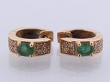 a pair of emerald and diamond earrings on a white surface