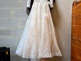 a white dress hanging on a wall next to a dresser