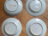 four blue and white plates sitting on top of a wooden floor