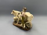 figurine of a woman on a horse with a man on a cow