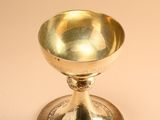 an antique silver plated cup on a stand on a beige background