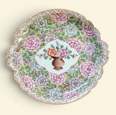 une assiette décorative sur laquelle figurent des fleurs et un vase