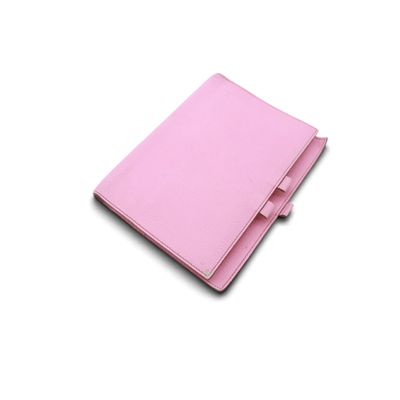 un carnet en cuir rose sur lequel repose un stylo, posé sur une surface blanche