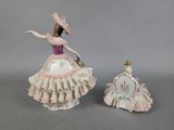 pair of porcelain figurines of a woman in a pink dress and a chair