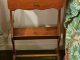 a small table with a lamp on top of it next to a bed