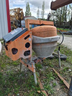 une machine qui se trouve dans l'herbe près d'un bâtiment
