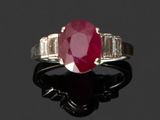 une bague ovale sertie d'un rubis et de diamants en taille baguette sur un fond noir