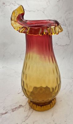 un vase rouge et jaune posé sur un plan de travail en marbre