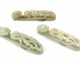 four pieces of jade carved hair clips on a white surface