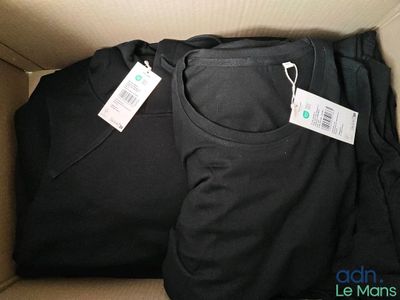 deux t-shirts noirs dans une boîte, avec leurs étiquettes