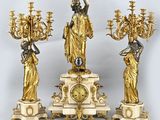 trois statues dorées et une horloge posée sur une table
