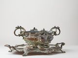 a silver plate with a bird on it on a stand