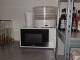a microwave sitting on top of a metal shelf in a kitchen